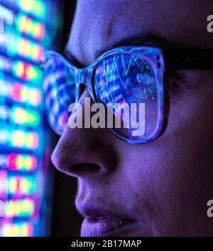 Female analyst viewing financial market data on a screen Stock Photo