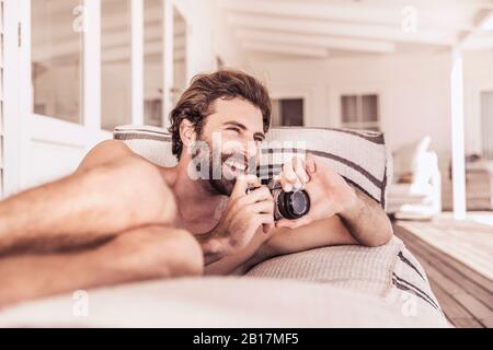 Happy young man with vintage camera relaxing on a veranda Stock Photo
