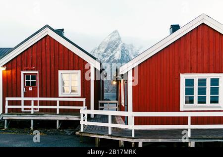 Red huts and snowcapped mountain at the coast, Hamnoy, Lofoten, Norway Stock Photo