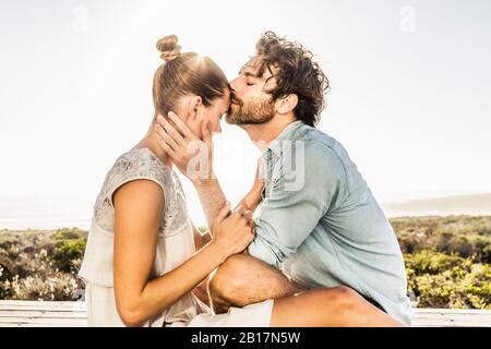 Affectionate young couple on terrace at the coast in summer Stock Photo