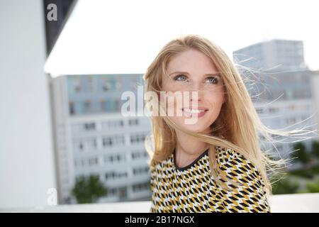 Portrait of smiling blond young woman with windblown hair Stock Photo