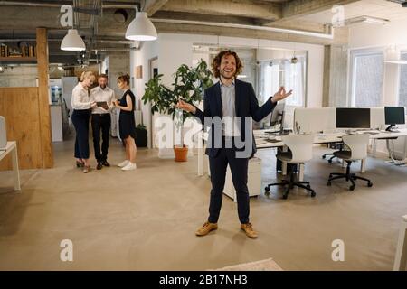 Happy businessman in office with colleagues in background Stock Photo
