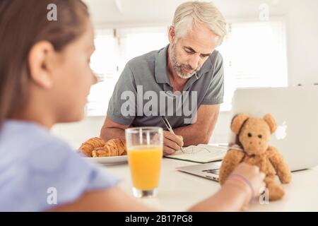 Mature man with daughter working in kitchen at home Stock Photo