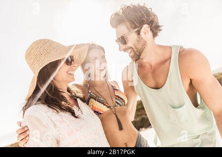 Two happy women and a man socializing outdoors in summer Stock Photo