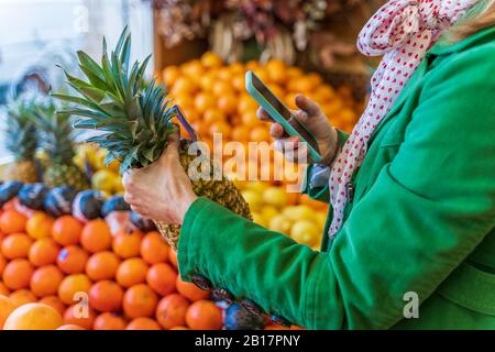 Woman using smartphone app to check a pinapple Stock Photo