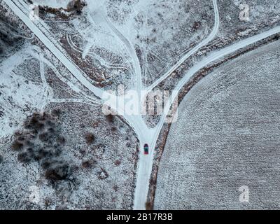 Russia, Moscow Oblast, Aerial view of car driving along country road past snow-covered fields Stock Photo