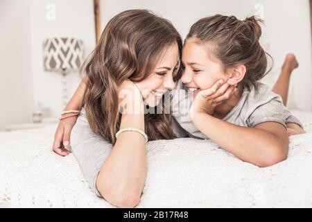 Happy mother and daughter lying together on bed having fun Stock Photo