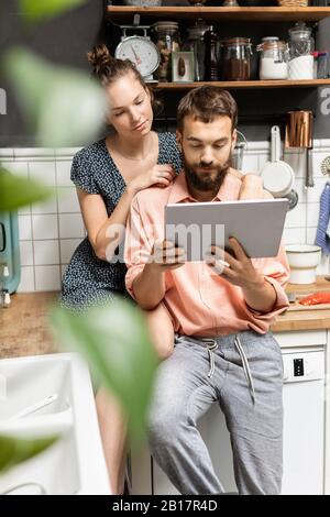Young couple using digital tablet in kitchen Stock Photo