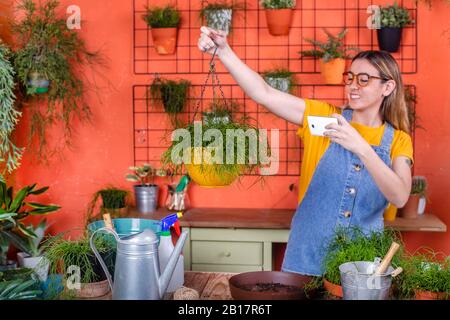 Young woman taking cell phone picture of her Rhipsalis plant Stock Photo