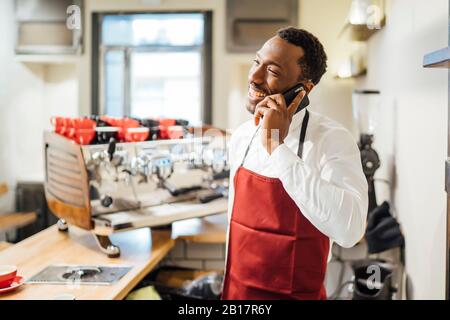 Happy barista on the phone in a coffee shop Stock Photo
