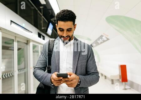 Young businessman using cell phone in subway station Stock Photo