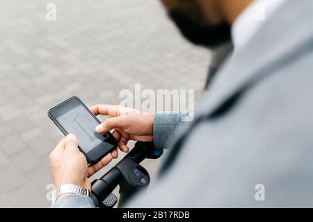Close-up of businessman with electric scooter using cell phone Stock Photo