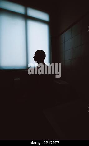 Silhouette of man sitting in bathroom Stock Photo