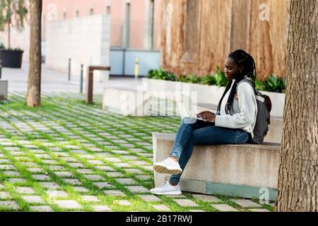 Female student using laptop on a bench Stock Photo