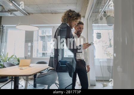 Two businessmen sharing tablet in office Stock Photo