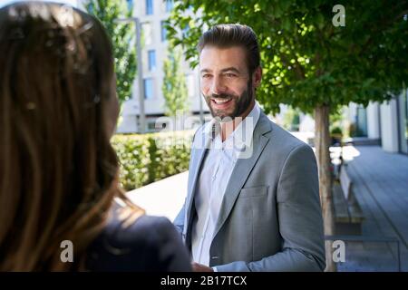 Smiling businessman looking at businesswoman in the city Stock Photo