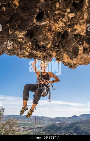 Female climber abseiling from rock face Stock Photo