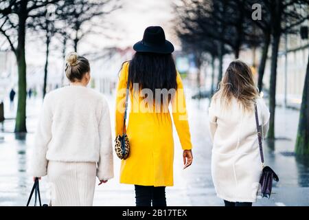 Rear view of girlfriends walking in the city on a rainy day Stock Photo