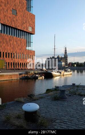 Belgium, Antwerp, Museum aan de Stroom (MAS) by river with Maison Mason in background, sunset Stock Photo