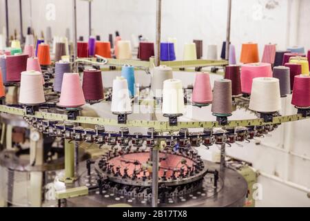 Multicolored cotton reels on a machine in a factory Stock Photo