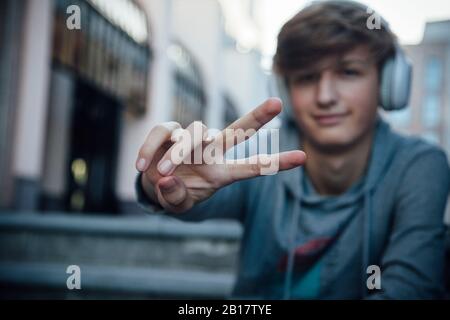 Portrait of teenager with headphones showing victory sign Stock Photo