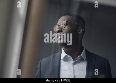 Young businessman wearing glasses looking out of window Stock Photo