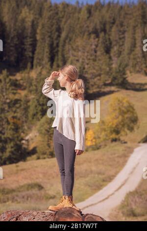Young girl balancing on a tree trunk, looking at distance