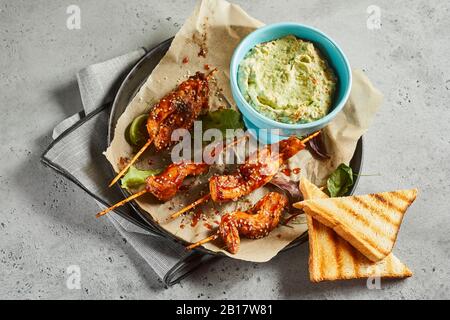 Toasts, grilled chicken skewers and bowl of salsa verde sauce Stock Photo