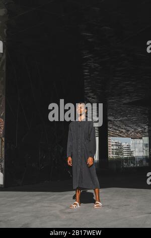 Young man wearing black kaftan standing outdoors Stock Photo