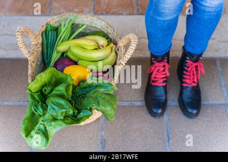 Woman standing by basket full of organic fruit and vegetables Stock Photo