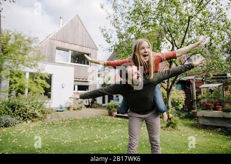 Cheering couple pretending to fly, standing in their garden Stock Photo