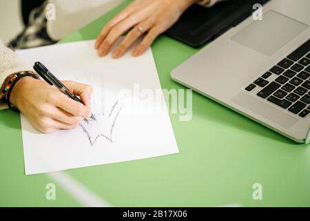 Close-up of woman at desk in office drawing on paper Stock Photo