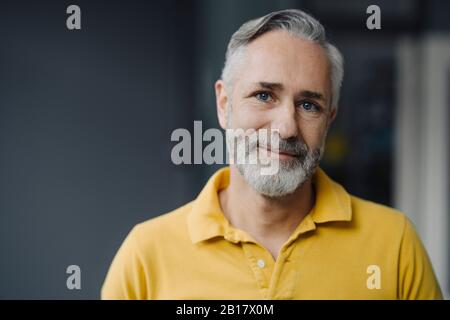 Portrait of smiling mature man with grey beard and blue eyes Stock Photo
