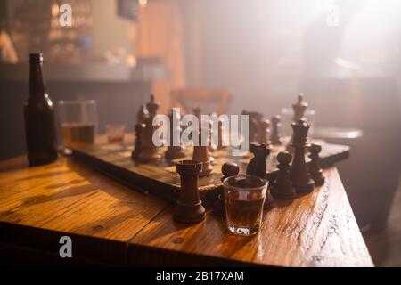 Old wooden chess board and drink on table in a pub Stock Photo