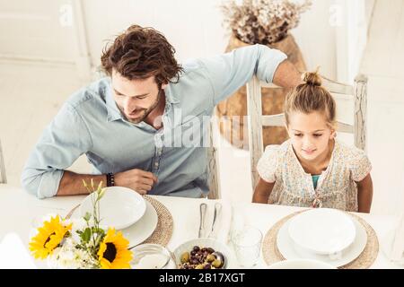 Father and daughter sitting at dining table Stock Photo