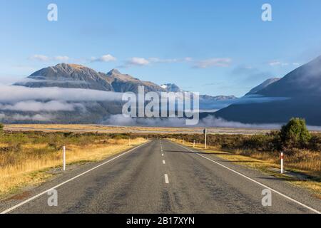 New Zealand, Fog floating over empty State Highway 73 with mountains in background Stock Photo