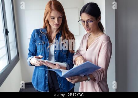 Businesswomen using digital tablet and looking at documents in the office Stock Photo