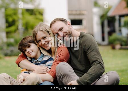 Happy family sitting on grass in their garden Stock Photo