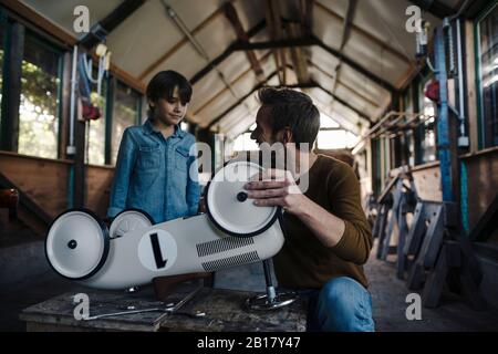 father and son repairing toy car in the barn Stock Photo