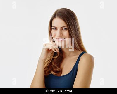 Portrait of smiling woman with long hair against white background Stock Photo