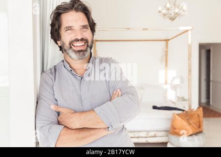 Portrait of happy bearded man leaning against a wall Stock Photo