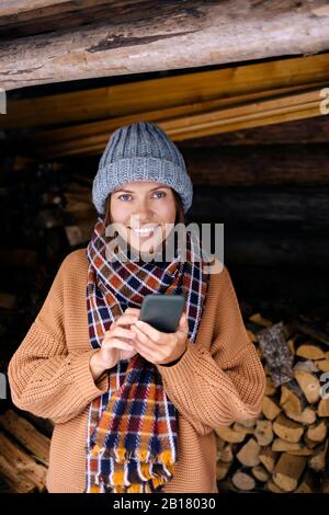 Young woman near a woodpile using smartphone Stock Photo