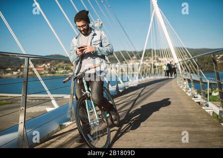 Young man commuting in the city with his fixie bike, using smartphone Stock Photo