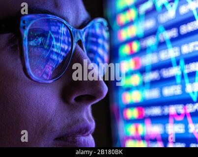 Female analyst viewing financial market data on a screen Stock Photo