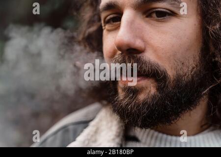 Portrait of young man, smoking outdoors Stock Photo
