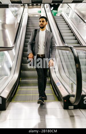 Casual young businessman on escalator Stock Photo
