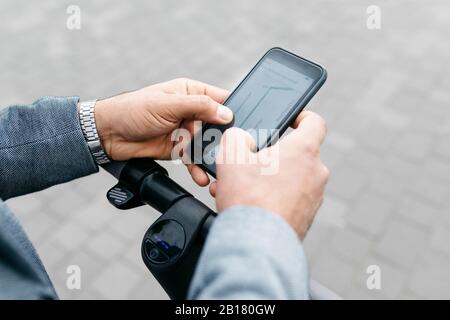 Close-up of businessman with electric scooter using cell phone Stock Photo