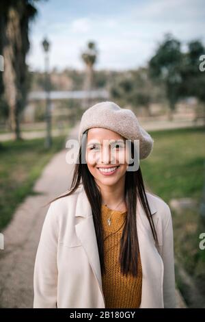 Portrait of smiling young woman with beret in a park Stock Photo