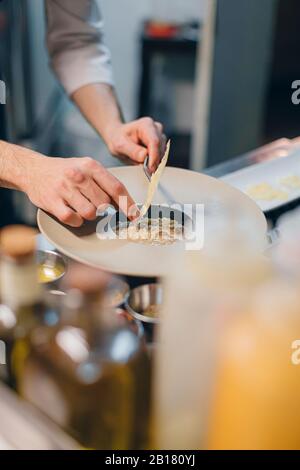 Chef preparing a dish with cheese in an Italian restaurant Stock Photo