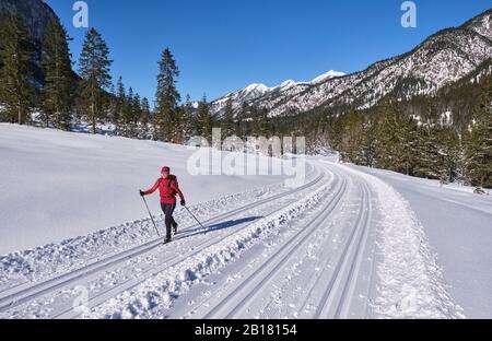 Senior woman doing cross-country skiing with karwendal mountains in background, Bavaria, Germany Stock Photo